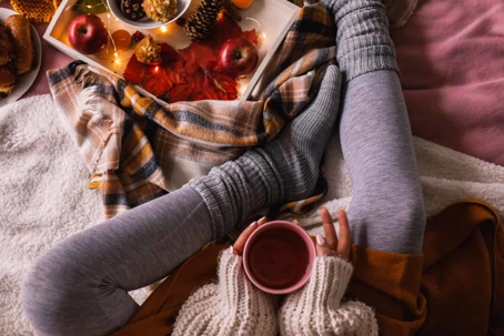 Lady sitting in leggings, sweater, with tea and fall decorations