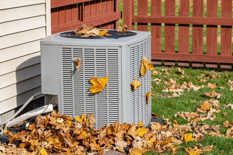 Dirty air conditioner outside, covered in leaves